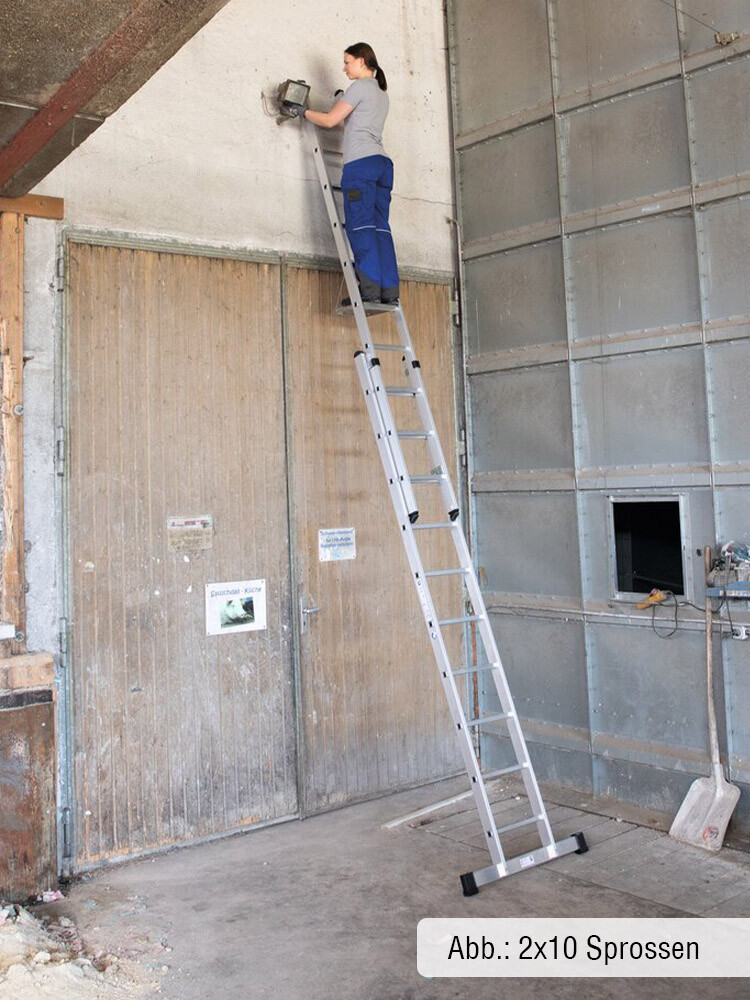 Frau in Arbeitskleidung steht auf einer 2-teiligen GÜNZBURGER Schiebeleiter vor einem Tor und repariert eine Lampe