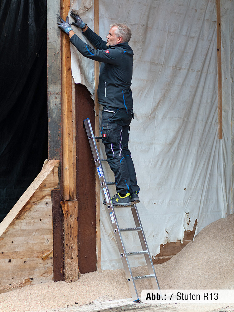 Mann in Arbeitskleidung steht auf einer 7-stufigen Anlegeleiter von KRAUSE, die an einer Wand anlehnt, und führt Arbeiten aus