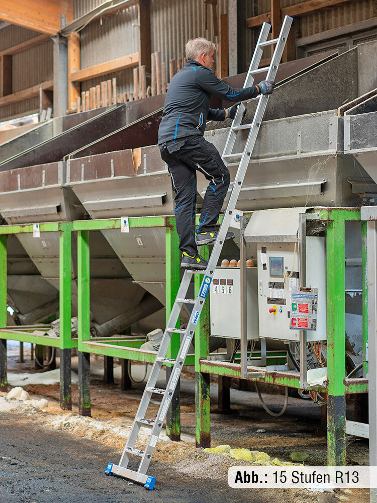 Person steigt eine 15-stufige Leiter mit Traverse hinauf, die an eine Maschine angelehnt ist und auf schlammigem Boden steht